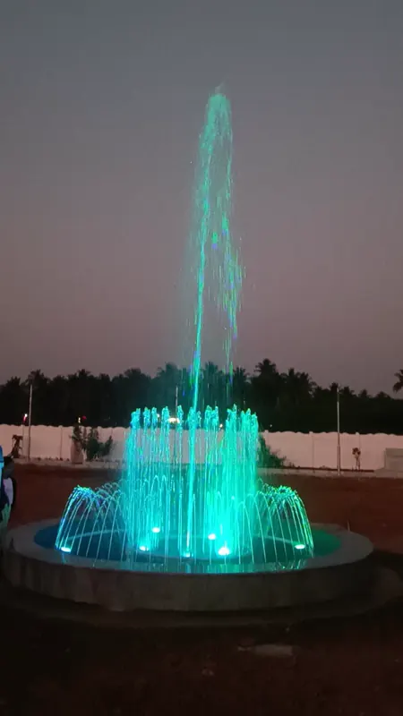 The park fountain lit in green at dusk